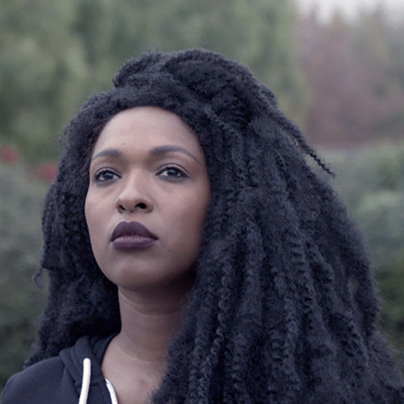 Film still of a Black woman looking into the distance.